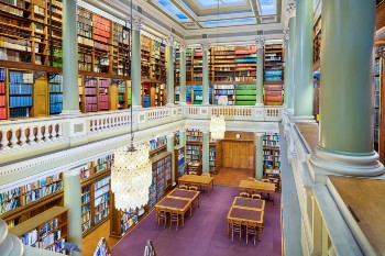 upper library at geological society with two levels of bookshelves, tall pillars and ornate chandeliers